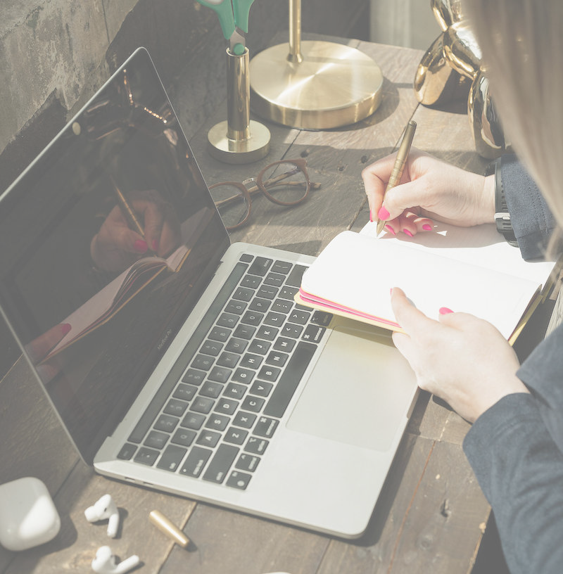 woman at desk with computer and notebook