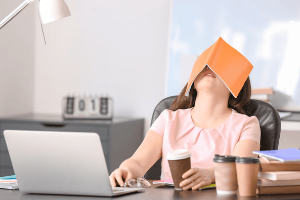 woman sleeping at desk with notebook over her face