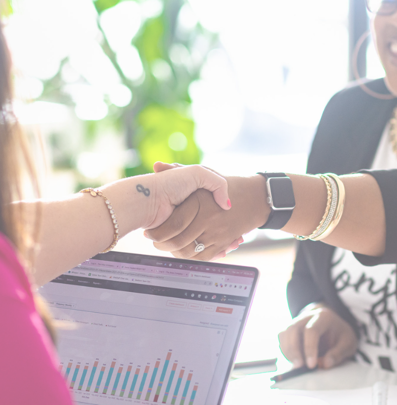 women shaking hands over a computer